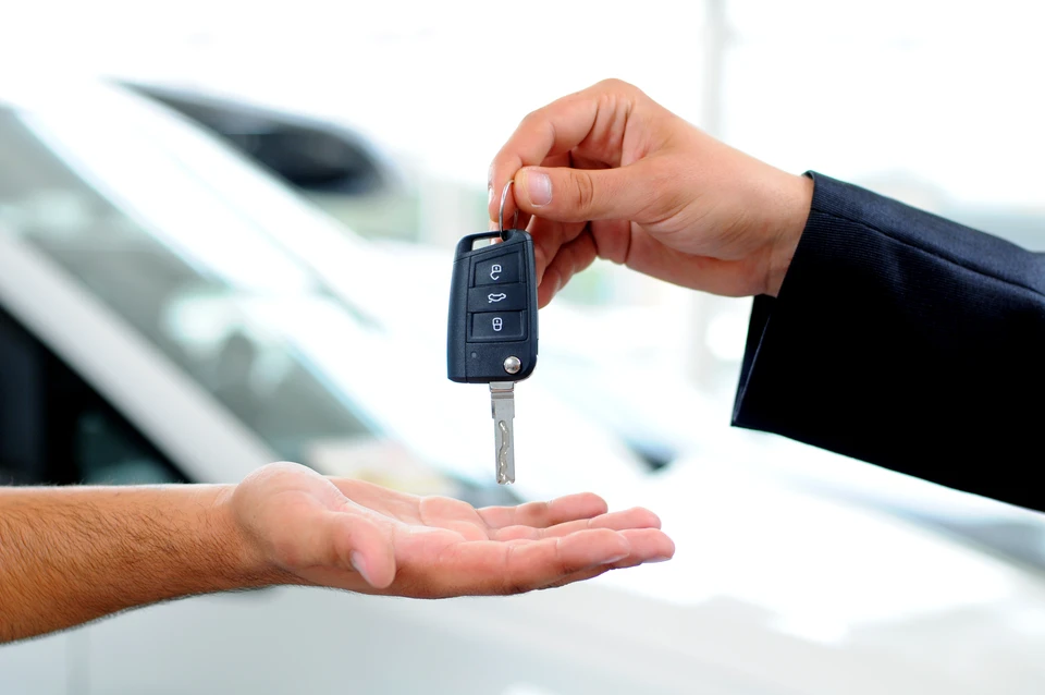 Scène extérieure de remise de clés automobiles entre deux personnes près d'un véhicule blanc
