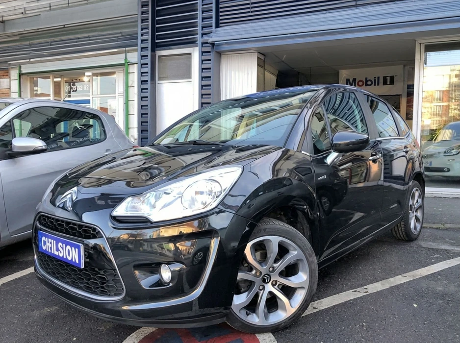 Véhicule Citroën C3 noire, stationnée devant un garage automobile
